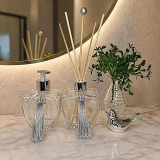 Kit lavabo premium decorativo com difusores de aromas, planta e pássaro, sobre balcão de mármore.
