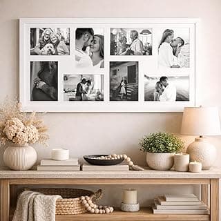 Painel multifotos de vidro branco com paspatur para oito fotos em preto e branco, montado na parede, com mesa de centro.