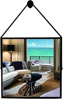 Espelho quadrado preto montado na parede refletindo uma sala com móveis e vista para o mar.