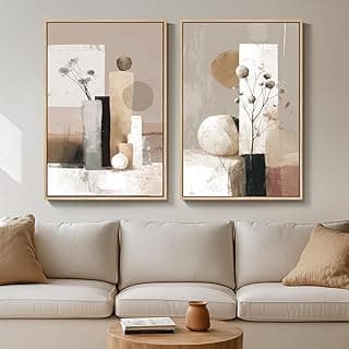 Quadros decorativos com moldura dourada pendurados acima de um sofá branco, arte abstrata em tons de bege e marrom.