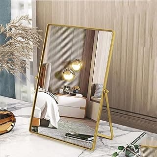 Espelho de maquiagem de mesa dourado com suporte ajustável, refletindo quarto com cama e almofadas