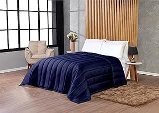 Quarto com cama, edredom azul marinho, mesa de cabeceira, cadeira de leitura e tapete.