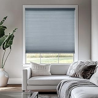 Persianas cinza fechadas em uma janela de uma sala de estar com vista para grama verde.