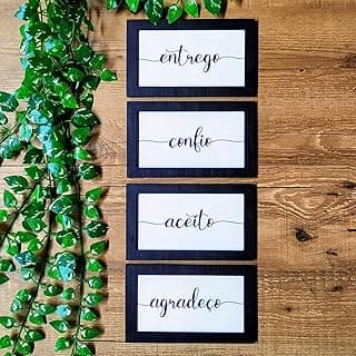 Quadros decorativos pretos com mensagens 'entrego', 'confio', 'aceito' e 'agradeço' em fundo de madeira