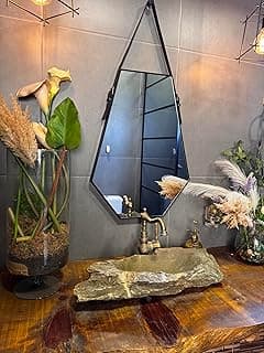 Espelho hexagonal decorativo preto em banheiro com pia de pedra e plantas