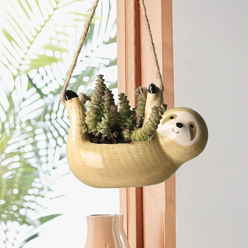 Vaso de planta pendurado em forma de preguiça amarelo claro com planta suculenta