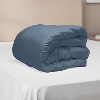 Edredom azul dobrado em cama branca, percal 400 fios, extra macio e hipoalergênico.