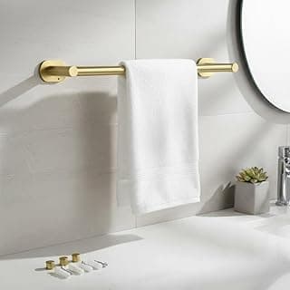 Suporte de toalha dourado em aço inox para banheiro, com toalha pendurada, espelho e planta no fundo.