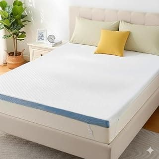 Cama com topper de colchão de espuma viscoelástica, cobertor, travesseiros e planta ao lado.