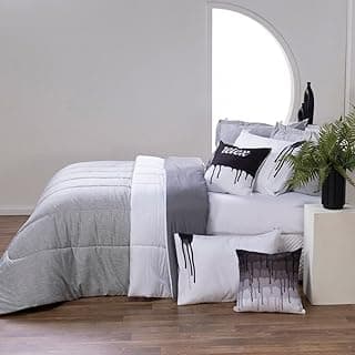 Quarto com cama queen size coberta por edredom cinza e branco, travesseiros combinando, janela circular e planta no vaso.